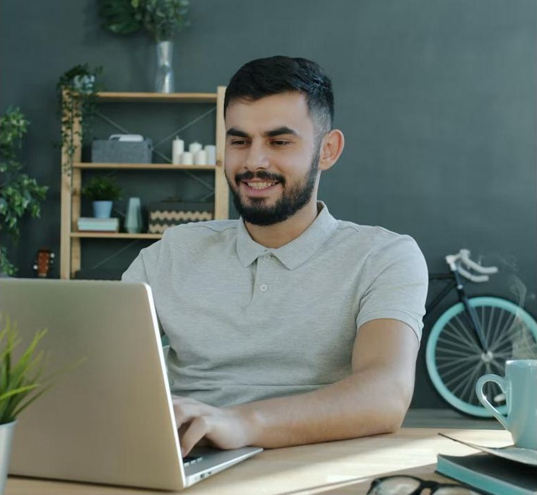 Homem sorrindo enquanto trabalha no notebook